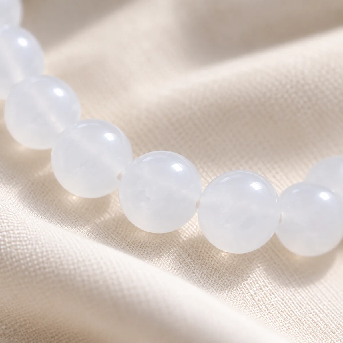 Collier jade blanc, rang de perles de néphrite, gros plan sur le grain et la translucidite de la pierre